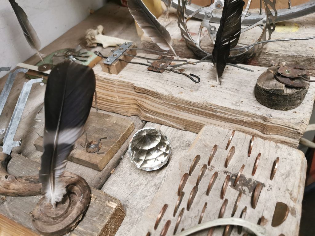 A feather and other metallic objects placed on a desk.