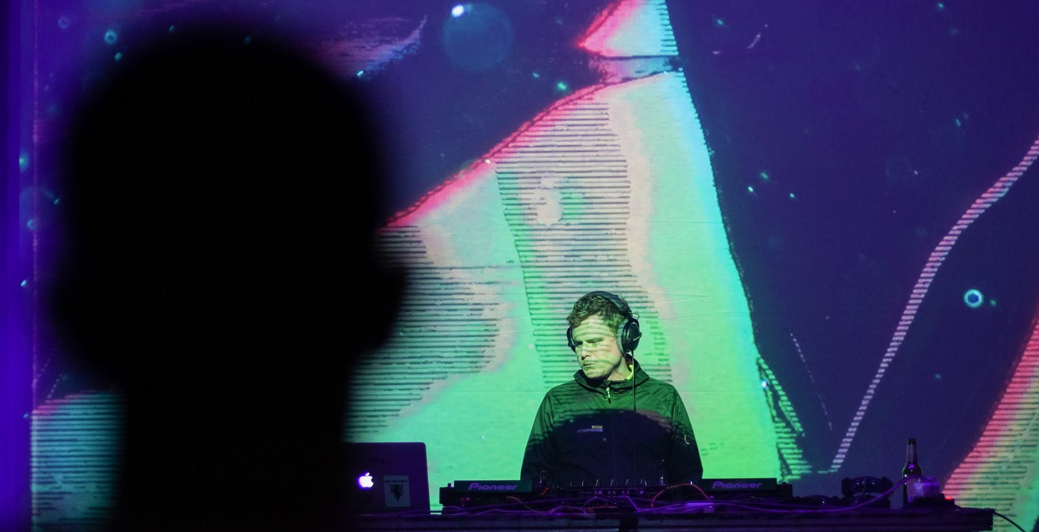 Konx-om-Pax performing at Mira Fest. Purple visuals are behind him. 