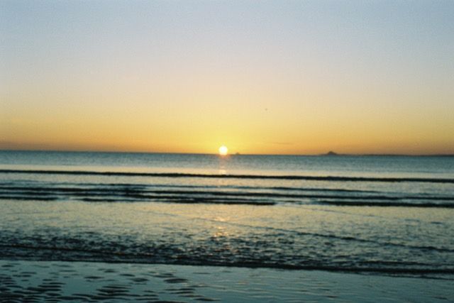 A film photo of a sunset over a calm sea.